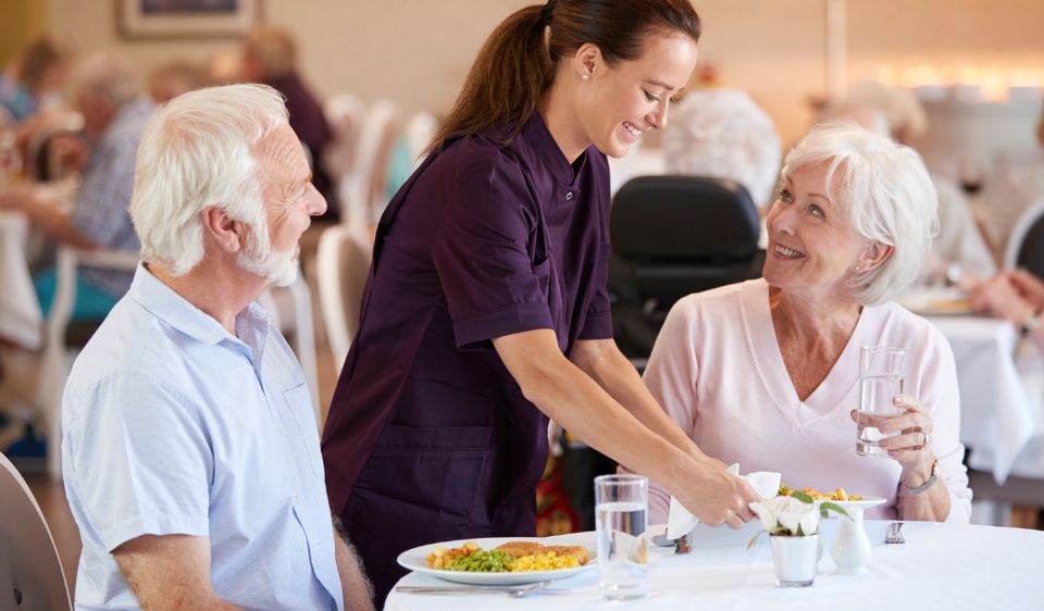 caregiver serving food to senior residents